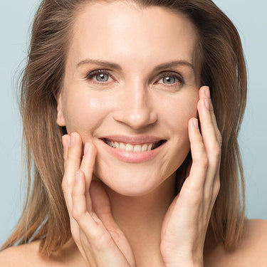 Model touching her face with a light blue background.