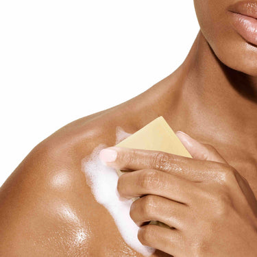 Image of a female model using a bar of Antü Refreshing Soap on her shoulder.